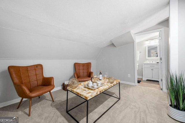 sitting room featuring baseboards, light carpet, and vaulted ceiling