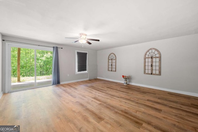 empty room with baseboards, ceiling fan, and wood finished floors