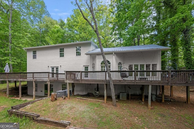 rear view of property featuring central AC unit, a deck, and metal roof