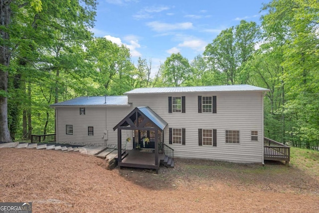 rear view of property featuring a wooden deck and metal roof