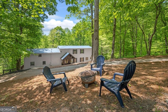 rear view of property with an outdoor fire pit and a wooded view