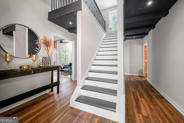staircase featuring plenty of natural light, a ceiling fan, and wood finished floors