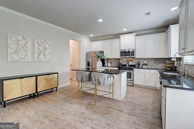 5601 Savannah River Rd, Atlanta, GA 30349 - kitchen with crown molding, appliances with stainless steel finishes, a breakfast bar area, white cabinetry, and decorative backsplash
