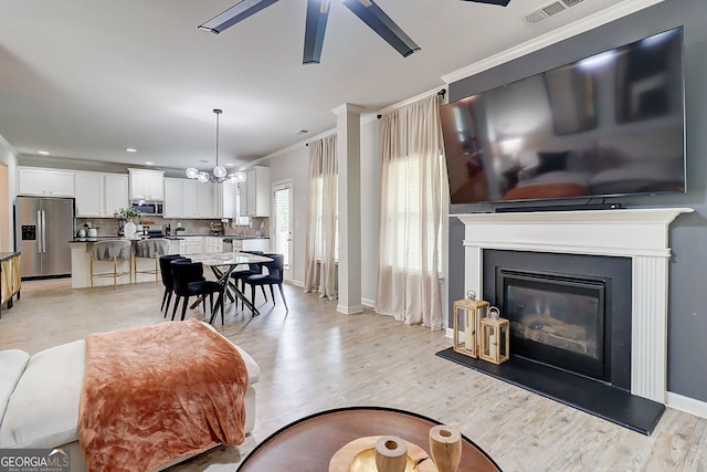 5601 Savannah River Rd, Atlanta, GA 30349 - living room with ceiling fan, visible vents, light wood-type flooring, a glass covered fireplace, and ornamental molding