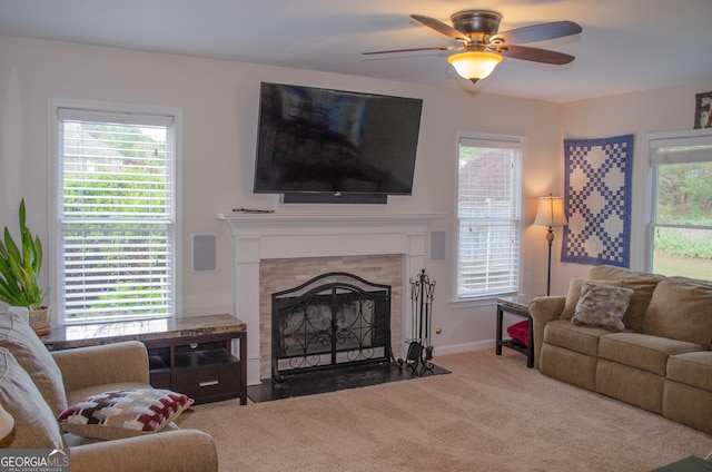 carpeted living room with a fireplace with flush hearth, baseboards, and ceiling fan