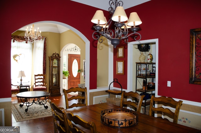 dining area featuring arched walkways, a chandelier, and hardwood / wood-style floors