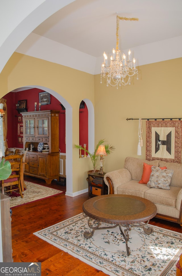 living area with arched walkways, wood finished floors, and a chandelier