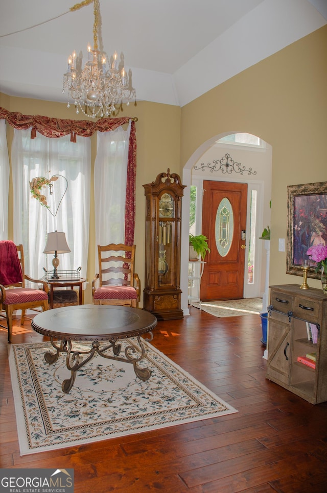 interior space featuring arched walkways, a notable chandelier, lofted ceiling, and hardwood / wood-style flooring