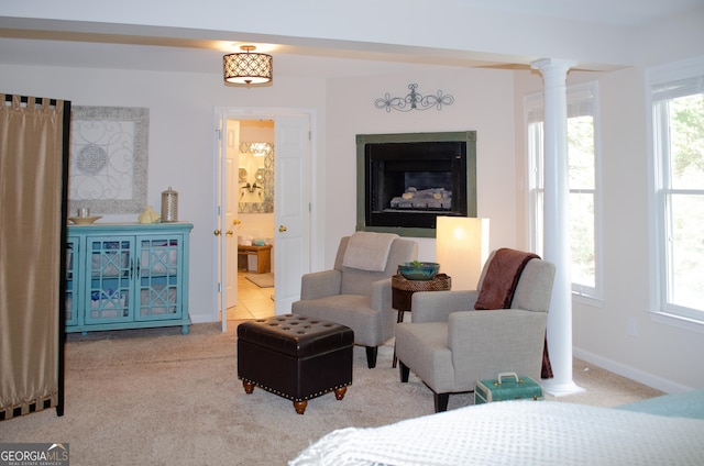 carpeted bedroom featuring ensuite bathroom, decorative columns, baseboards, and a fireplace