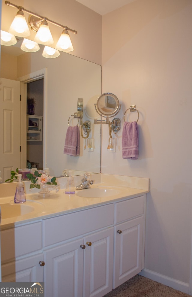 bathroom featuring double vanity, baseboards, and a sink