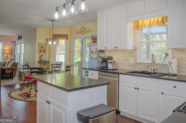 kitchen featuring decorative backsplash, dark countertops, white cabinetry, a sink, and dishwasher