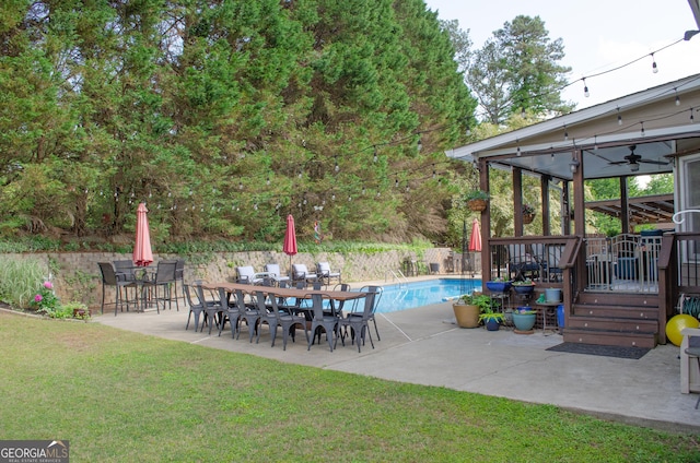 view of patio with a fenced in pool, fence, a ceiling fan, and a deck