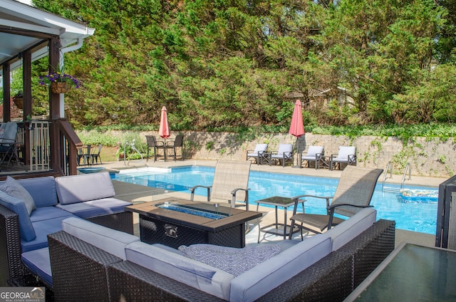 view of pool with a fenced in pool, a patio area, and an outdoor living space with a fire pit