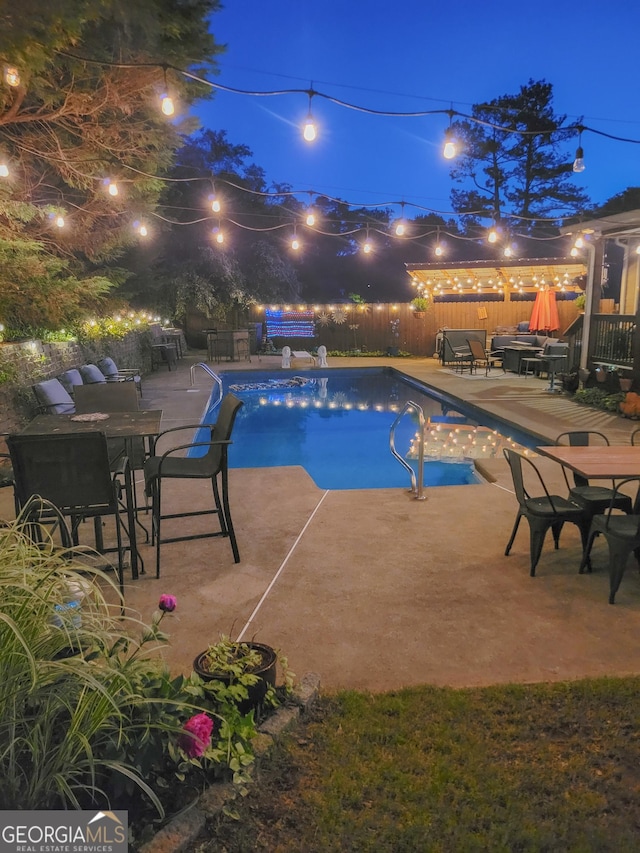 pool at night featuring a fenced in pool, a fenced backyard, and a patio area