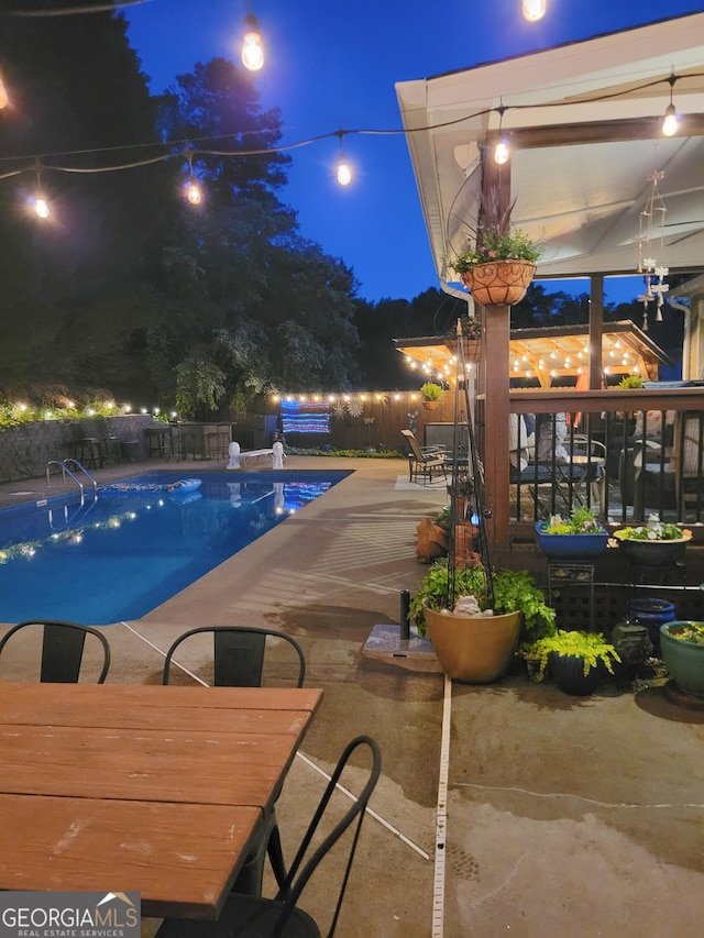 pool at twilight featuring a fenced in pool, a patio area, and fence