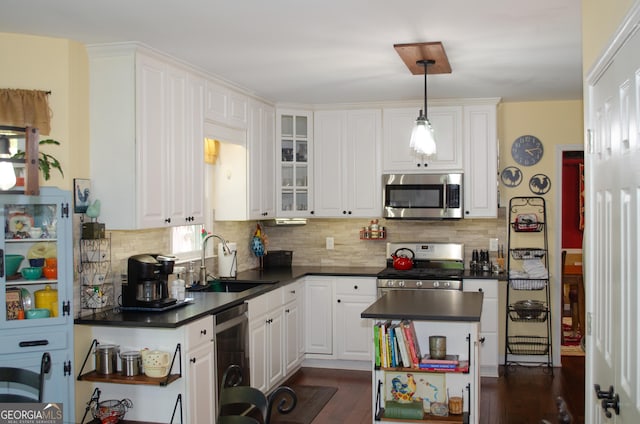 kitchen featuring white cabinetry, dark countertops, appliances with stainless steel finishes, and a sink