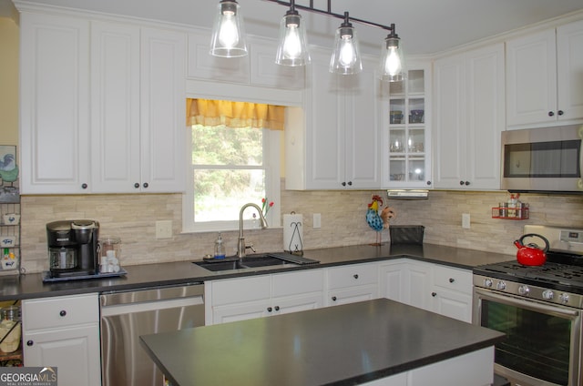 kitchen with white cabinets, dark countertops, appliances with stainless steel finishes, and a sink