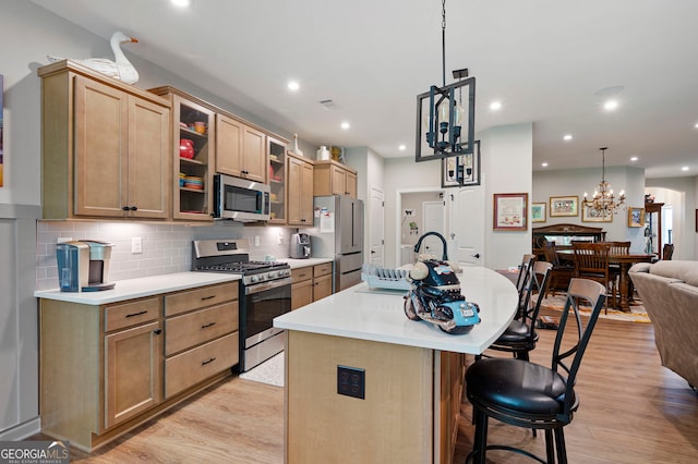 109 Aspen Way, Dallas, GA 30157 - kitchen with light countertops, a breakfast bar area, light wood-style floors, stainless steel appliances, and a kitchen island with sink