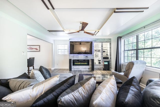 living area featuring baseboards, a ceiling fan, wood finished floors, and a fireplace