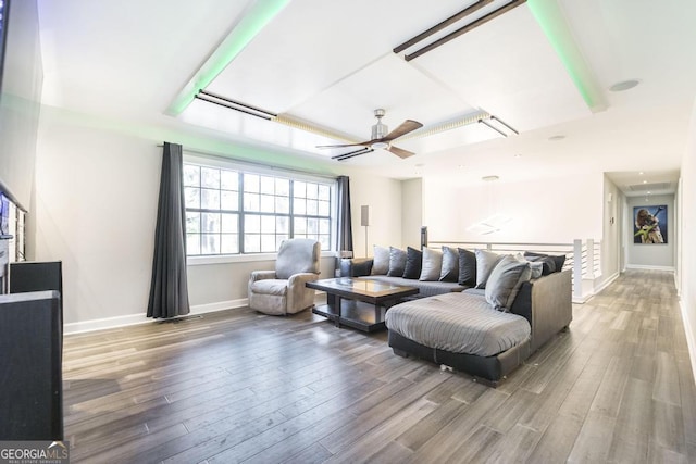 living room featuring baseboards, a ceiling fan, wood finished floors, and a tray ceiling