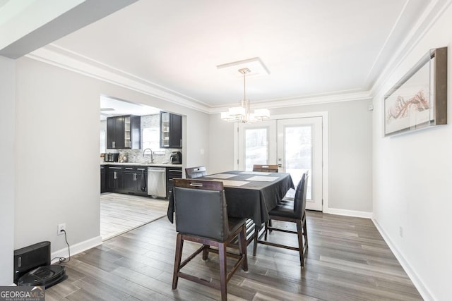 dining area featuring crown molding, baseboards, a chandelier, and wood finished floors