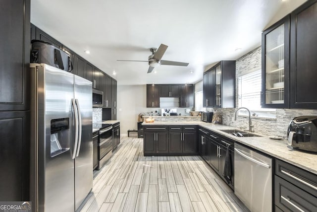 kitchen featuring a ceiling fan, a sink, appliances with stainless steel finishes, and backsplash