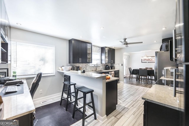 kitchen featuring a healthy amount of sunlight, baseboards, decorative backsplash, and ceiling fan with notable chandelier