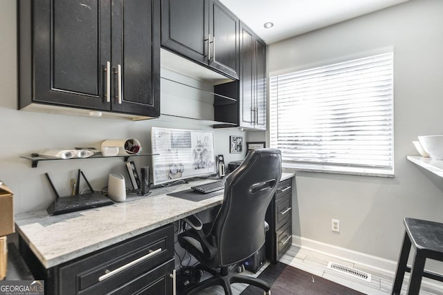 office area featuring baseboards, built in desk, and visible vents