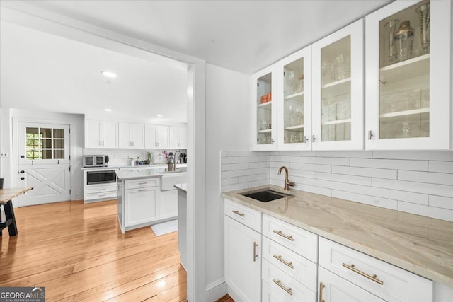 45 Michelle Cir NE, Atlanta, GA 30342 - kitchen with a sink, tasteful backsplash, white cabinets, light wood finished floors, and glass insert cabinets