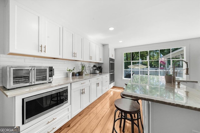45 Michelle Cir NE, Atlanta, GA 30342 - kitchen with stainless steel appliances, light wood finished floors, light stone countertops, white cabinets, and recessed lighting
