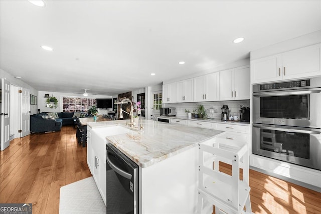 45 Michelle Cir NE, Atlanta, GA 30342 - kitchen with appliances with stainless steel finishes, white cabinetry, a center island with sink, recessed lighting, and backsplash