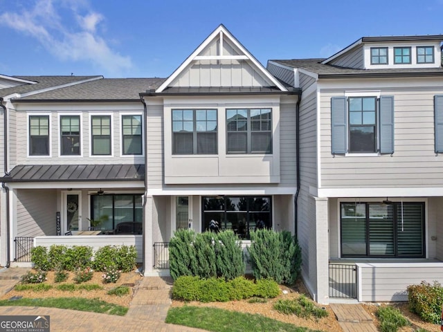 townhome / multi-family property with fence, a standing seam roof, a gate, board and batten siding, and metal roof