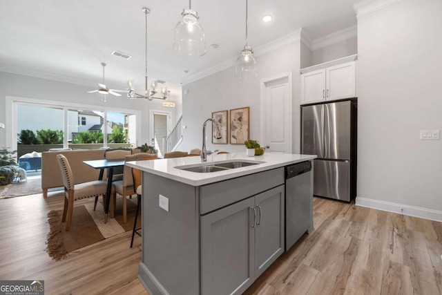 kitchen featuring crown molding, light countertops, a sink, gray cabinetry, and stainless steel appliances