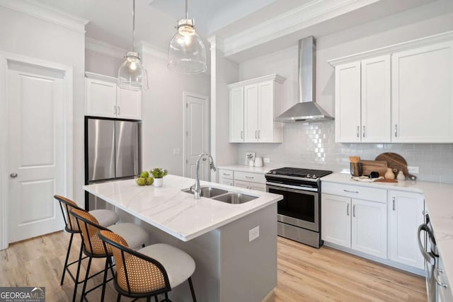 kitchen featuring crown molding, wall chimney exhaust hood, a sink, appliances with stainless steel finishes, and backsplash