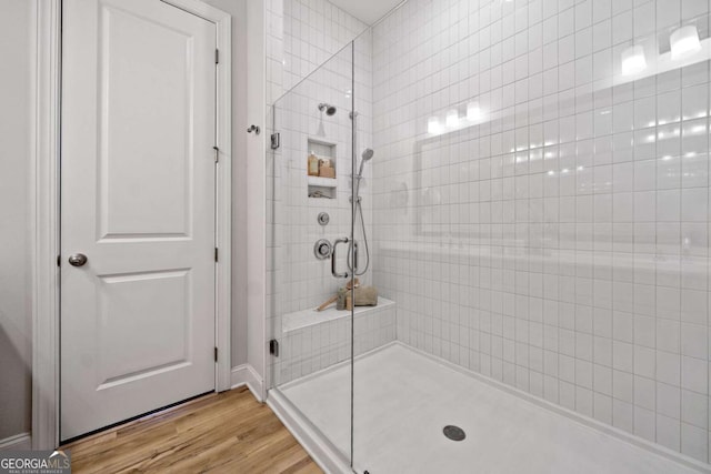 full bath with a tile shower and wood finished floors