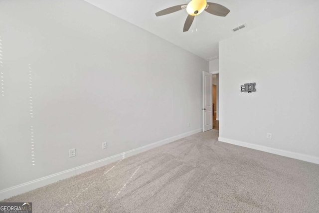 spare room featuring a ceiling fan, light colored carpet, visible vents, and baseboards