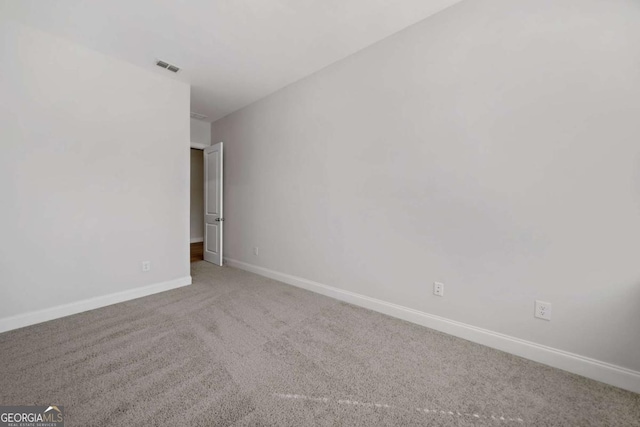 spare room with carpet floors, baseboards, and visible vents