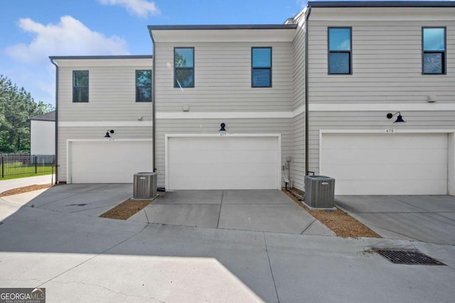 view of property featuring fence, central AC, driveway, and a garage