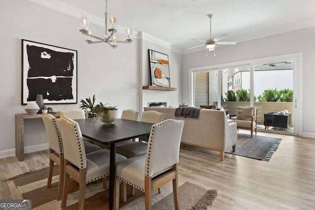 dining area with light wood-style floors, baseboards, ornamental molding, and ceiling fan with notable chandelier