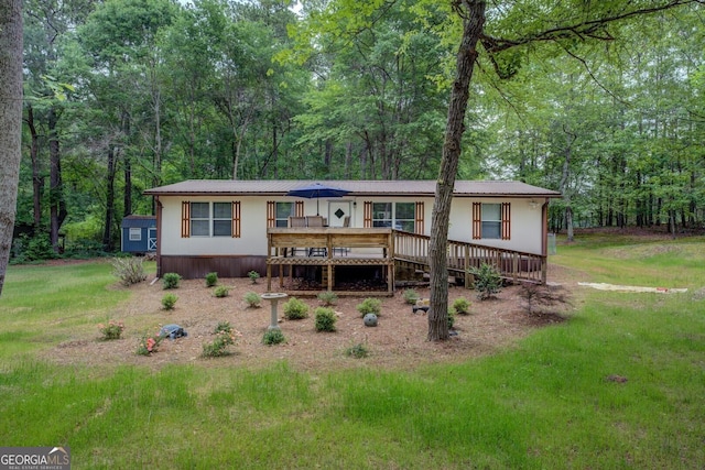 back of property featuring a yard, a deck, and metal roof