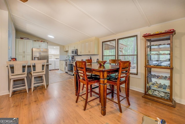 dining area with light wood-type flooring, baseboards, lofted ceiling, and washer and dryer