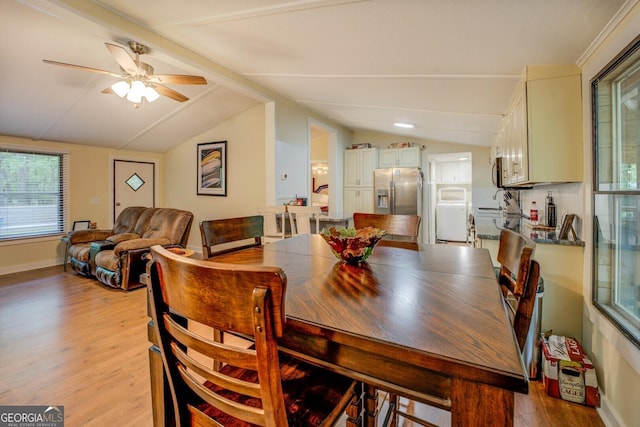 dining area with a ceiling fan, washer / clothes dryer, vaulted ceiling, baseboards, and light wood finished floors