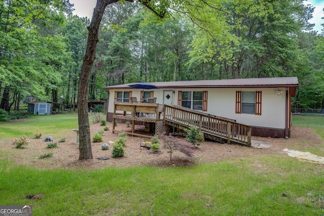 view of front of home with fence, a storage unit, a front yard, an outbuilding, and metal roof