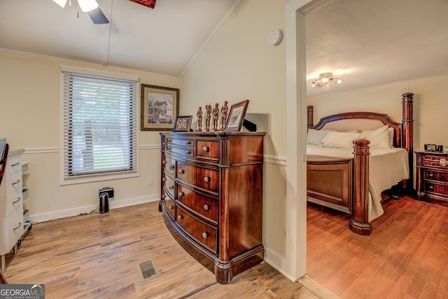 bedroom with crown molding, lofted ceiling, wood finished floors, and visible vents