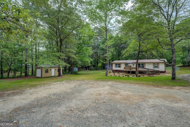 view of front of home with an outdoor structure, a wooden deck, a shed, and a front yard