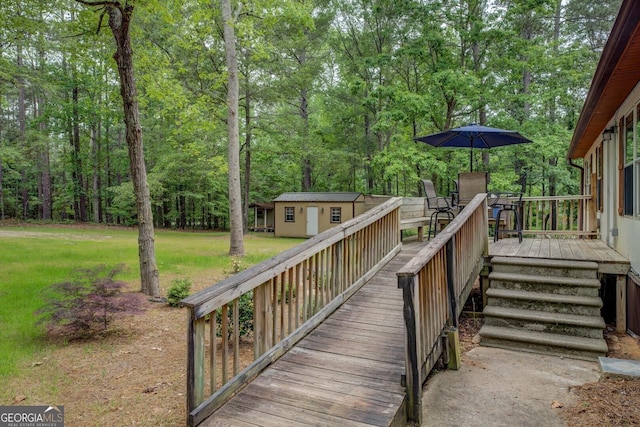 deck with a view of trees, an outdoor structure, and a yard