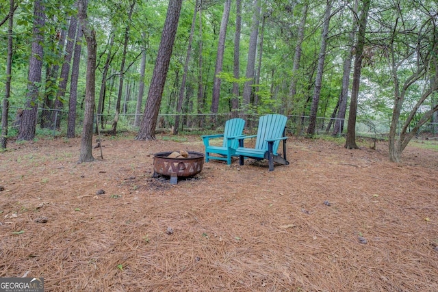 view of yard featuring a fenced backyard, an outdoor fire pit, and a wooded view