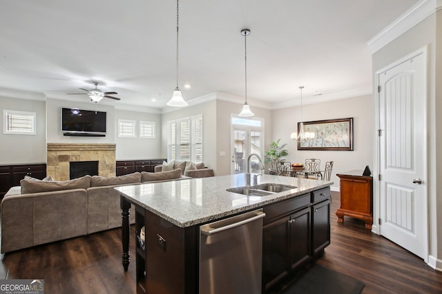 kitchen featuring a sink, a fireplace, ceiling fan with notable chandelier, stainless steel dishwasher, and dark wood-style floors