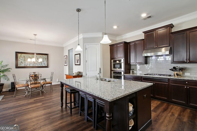 kitchen featuring visible vents, a sink, under cabinet range hood, stainless steel appliances, and an island with sink