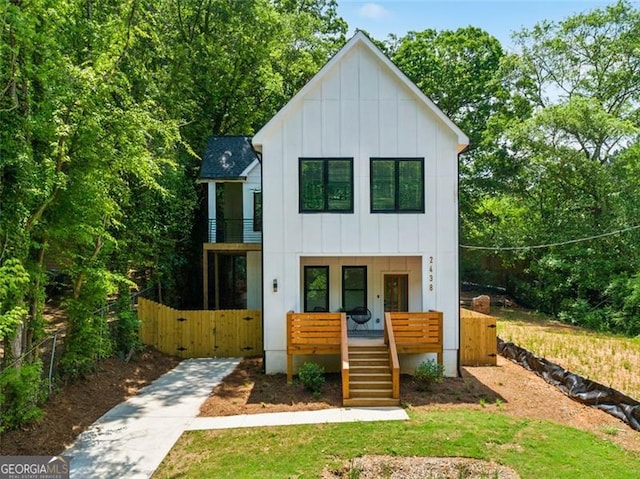 modern inspired farmhouse with fence, a balcony, a gate, board and batten siding, and a porch
